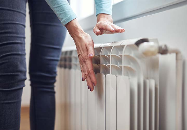 Gros plan sur deux mains tendues vers un radiateur à haut